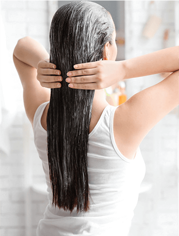 A woman is holding her hair in front of the mirror.